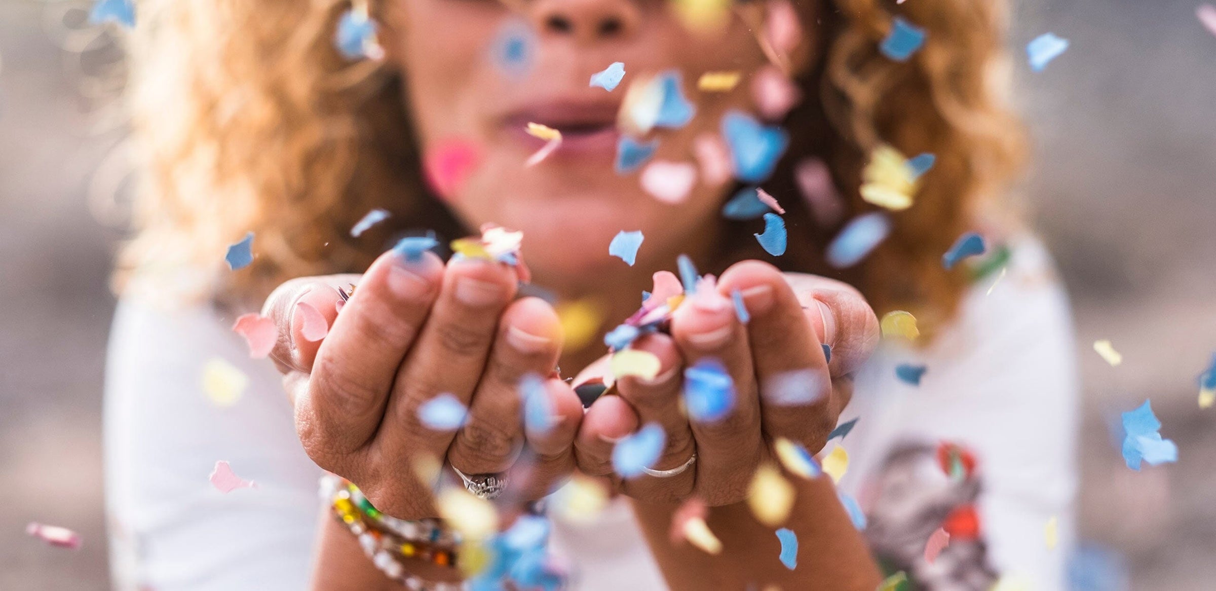 outstretched hands with confetti being blown into the air