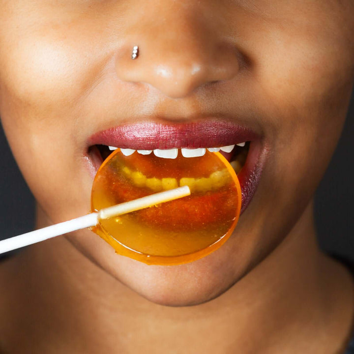 A woman eating a honey lollipop