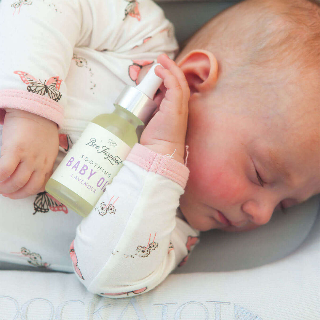 A sleeping baby holding a bottle of lavender baby oil