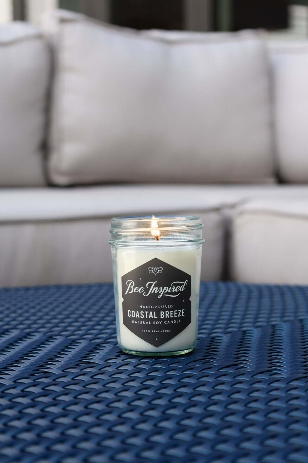 Coastal Breeze jelly jar candle burning on blue table