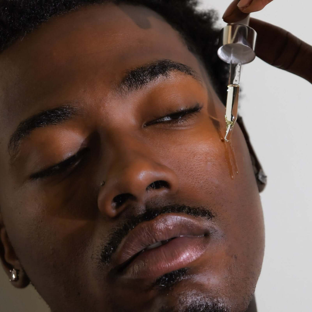 man drips Rose Garden face oil onto his cheek