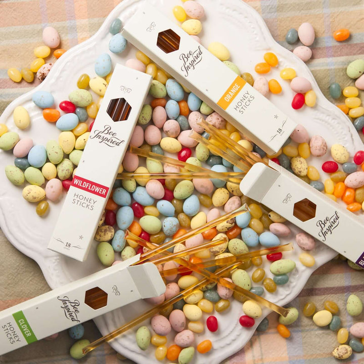 Boxes of varietal honey sticks on a plate of multicolored jelly beans
