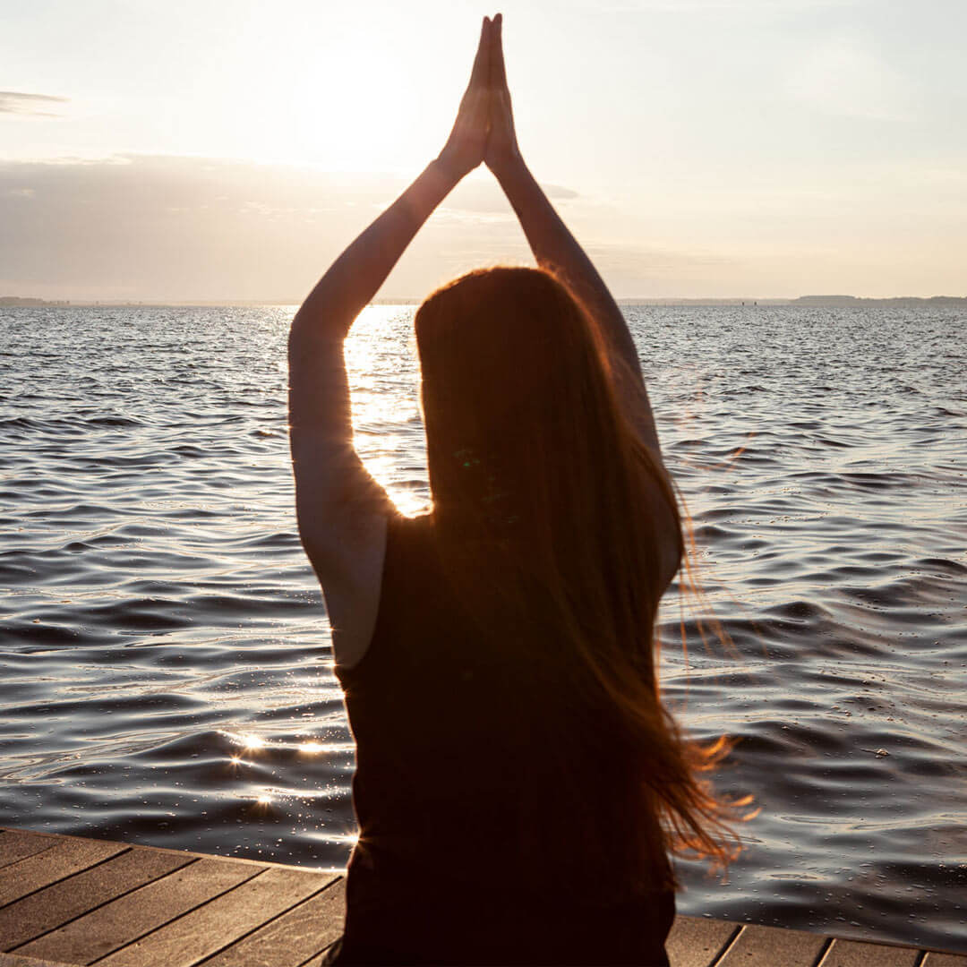 woman doing yoga on the dock by the water