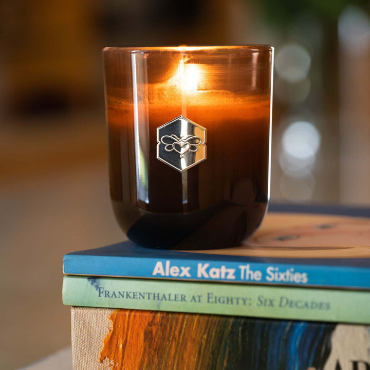 Luxe candle burning on stack of books