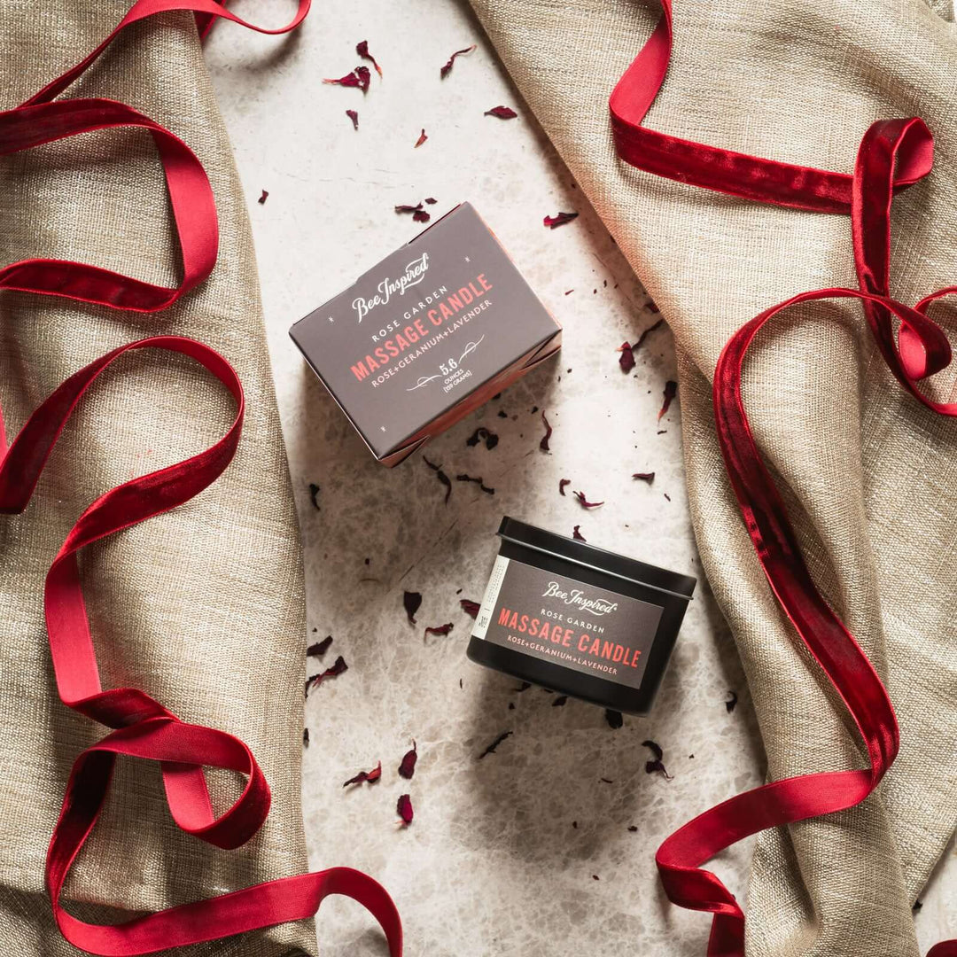 Rose Garden massage candle and box flat lay on fabric and red ribbon
