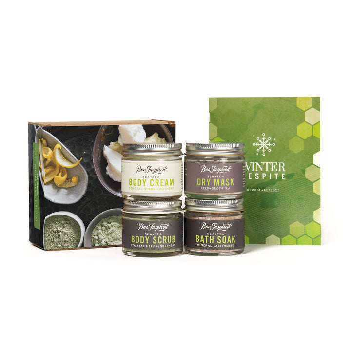 Set of body care products in the Petite Winter Respite Set including cream, scrub, mask, and soak with a branded box on a white background.