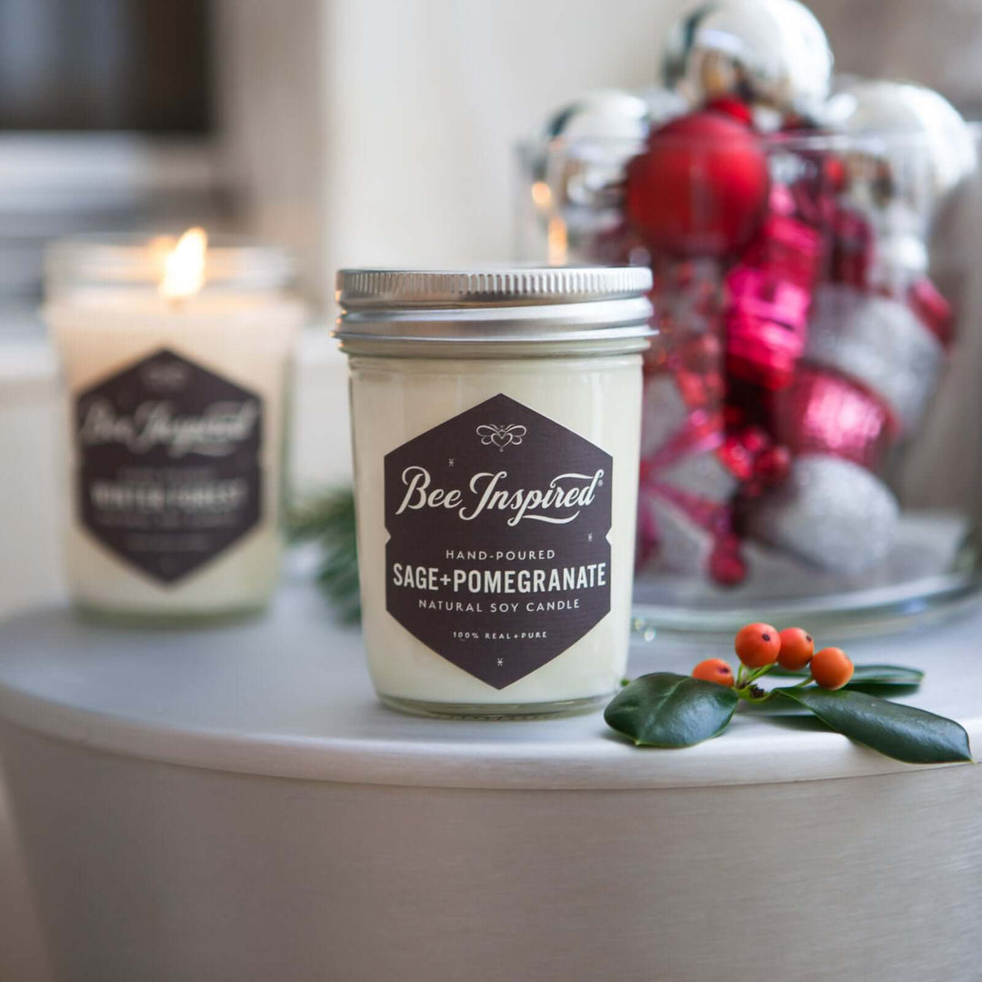 Sage+Pomegranate and Winter Forest jelly jar candles in front of decorative ornaments