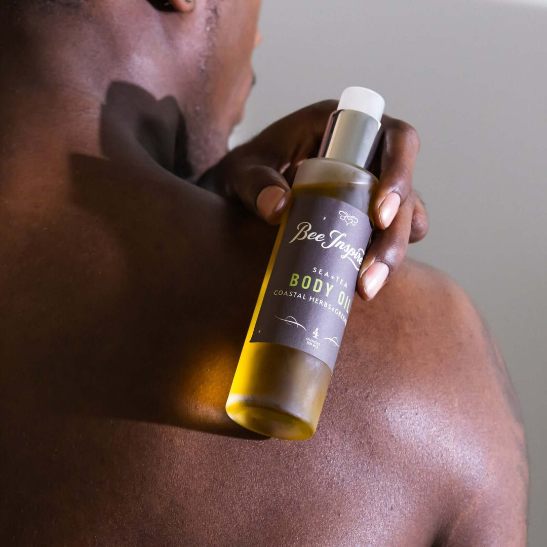 man holds 4oz bottle of Sea+Tea body oil over his shoulder