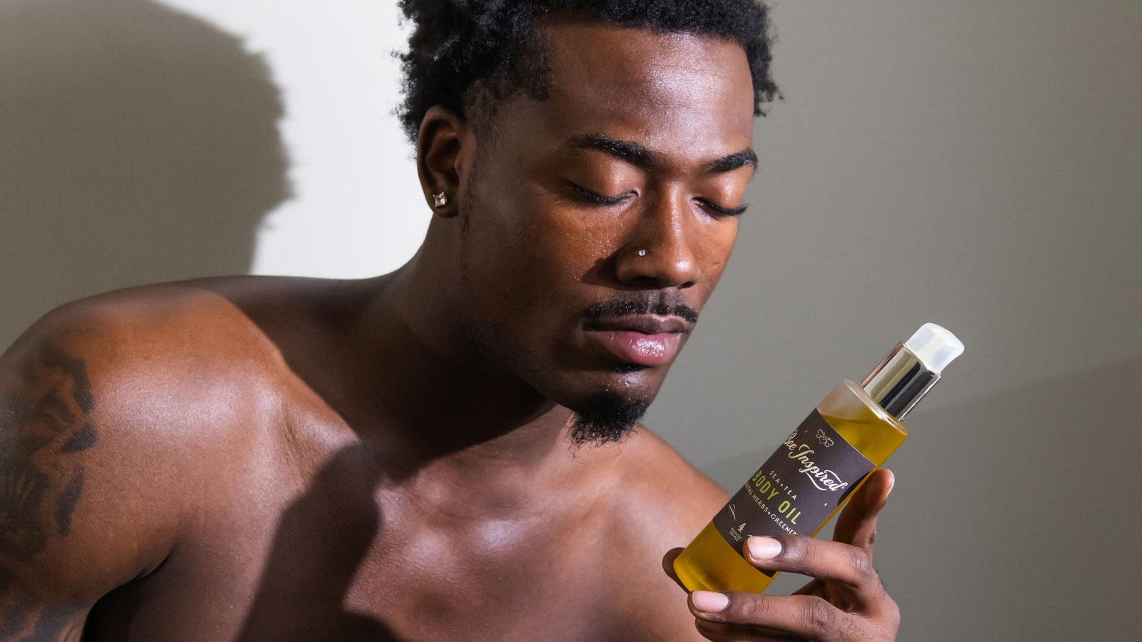 man looking at and holding bee inspired sea + tea body oil