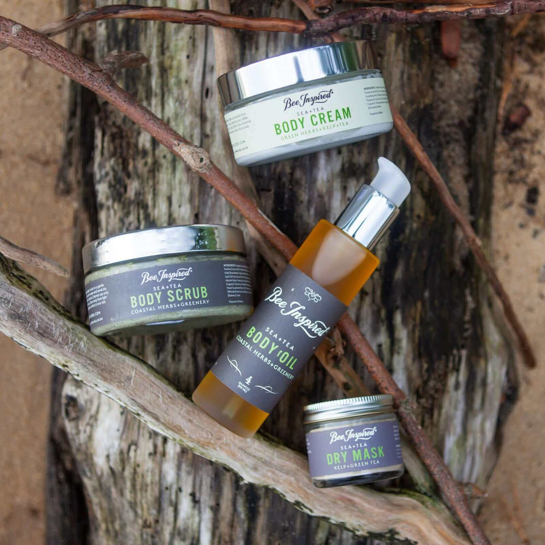 Sea+Tea body cream, scrub, body oil, and dry mask against driftwood