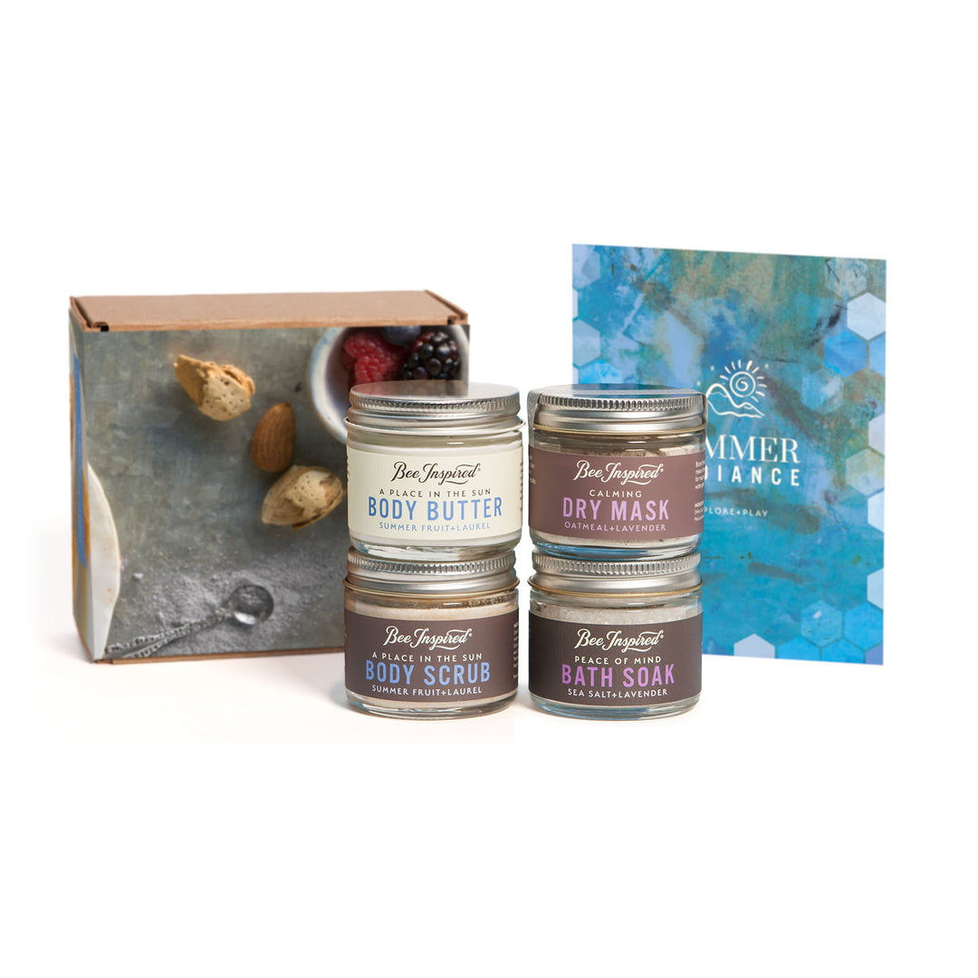 Set of body care products in the Petite Summer Radiance Set including body butter, scrub, mask, and soak with a branded box on a white background.