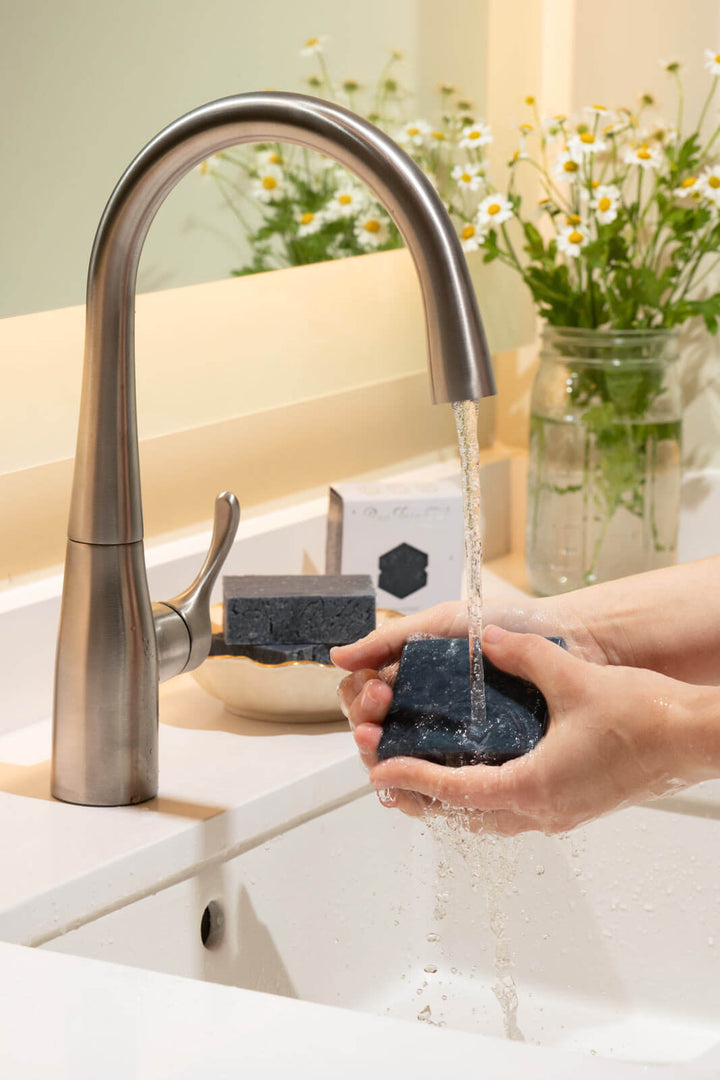 Person washes their hands with black clay bar soap