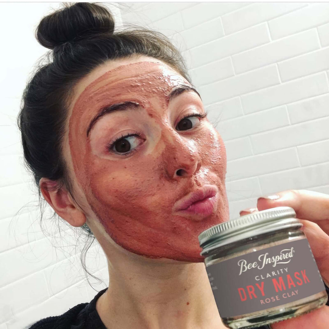 Woman wearing Clarity face mask holds jar of dry mask