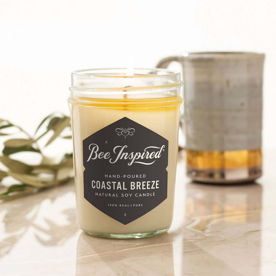 Coastal Breeze jelly jar candle burning next to mug