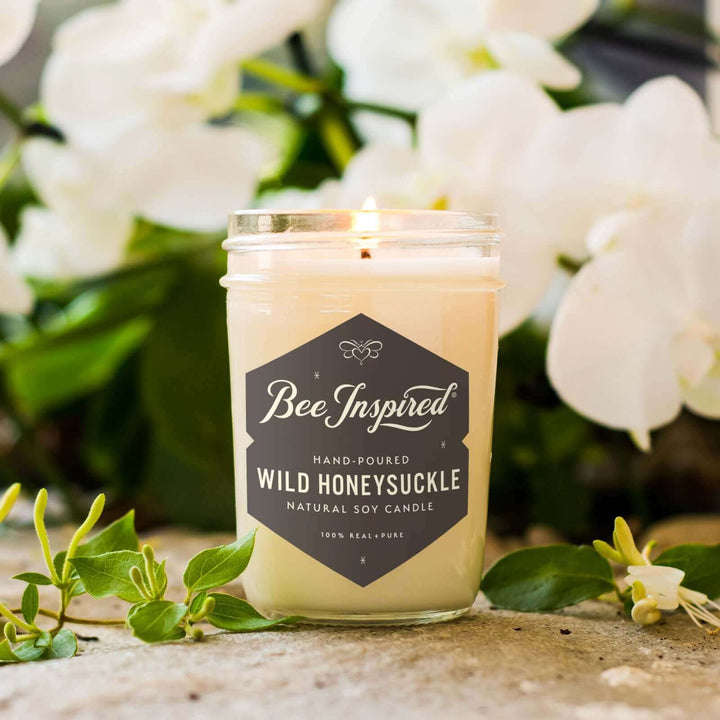 Wild Honeysuckle jelly jar candle burning in front of white flowers