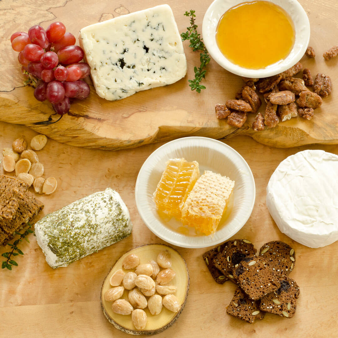 Charcuterie board with grapes, cheese, honey, raw honeycomb, and crackers