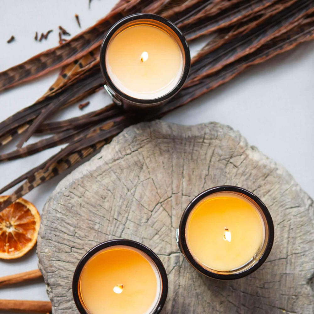 Three luxe candles burning on a log aerial view