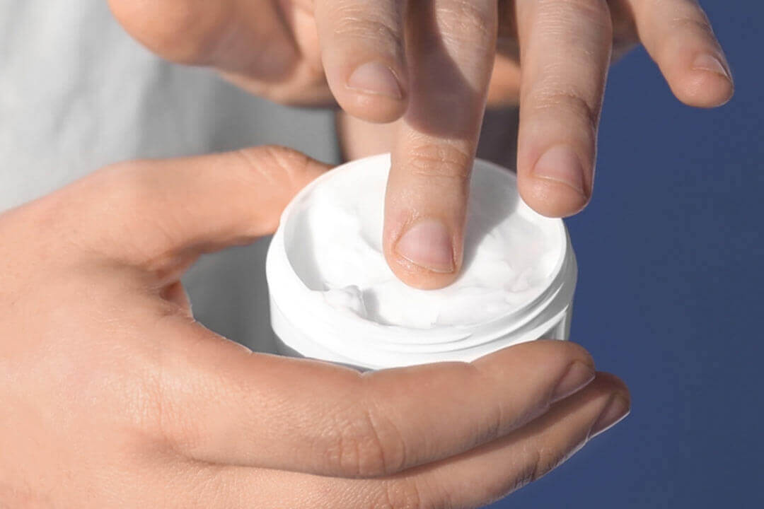 Close-up of a person putting body butter on their hand
