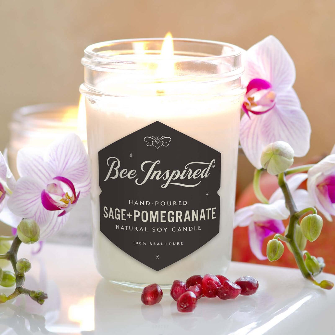 Sage+Pomegranate jelly jar candle burning next to orchids and pomegranate seeds
