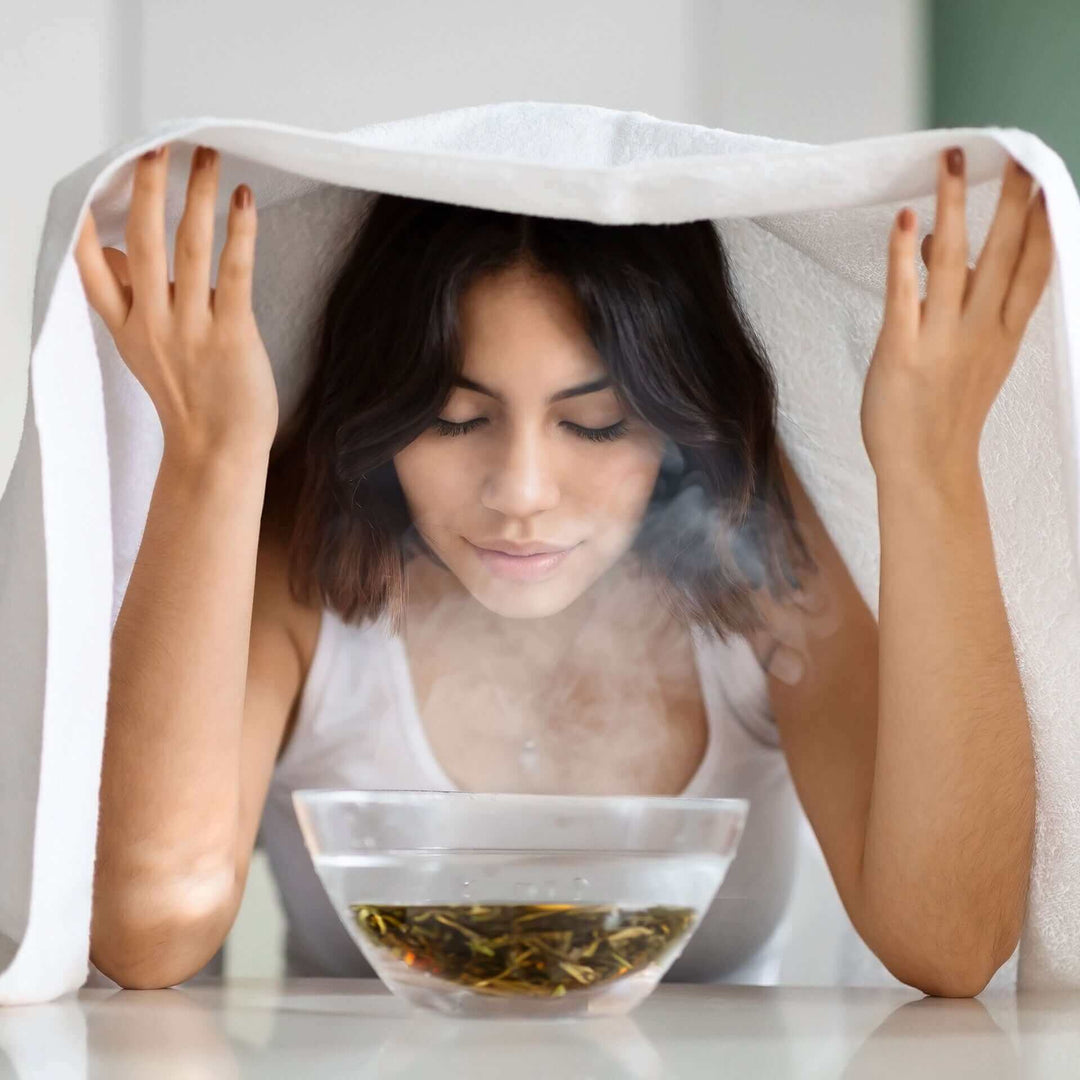 a woman steaming over a bowl of brewed tea