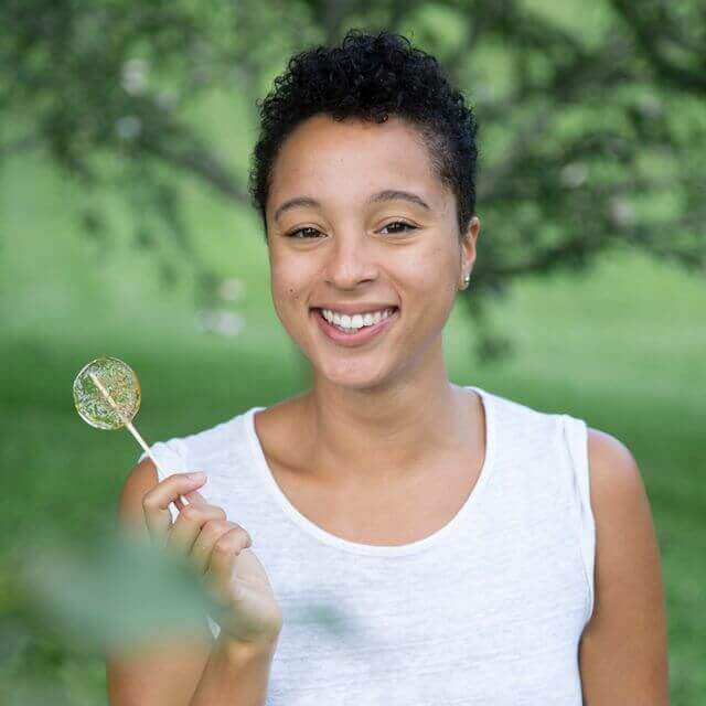 woman in nature holding a honey lollipop from bee inspired honey retail store in owings mills