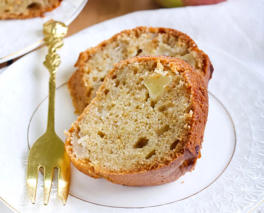 apple cake on white plate with gold fork on table