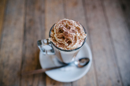 hot chocolate in a mug topped with whipped cream and cocoa powder