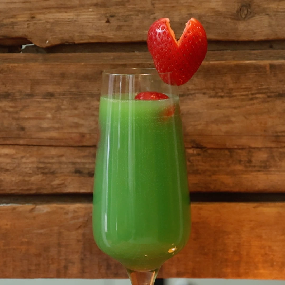 grinch mimosa garnished with a strawberry