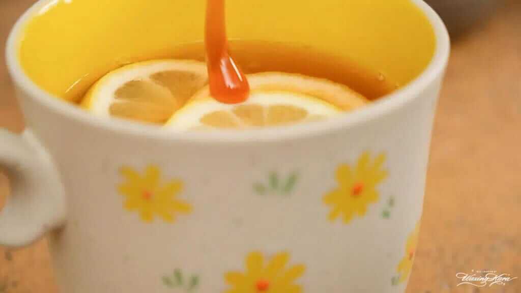 Adding honey to a mug of tea with lemon slices