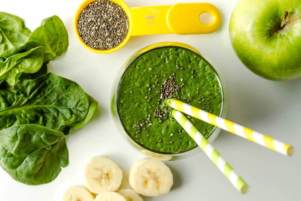 bee green smoothie surrounded by raw ingredients