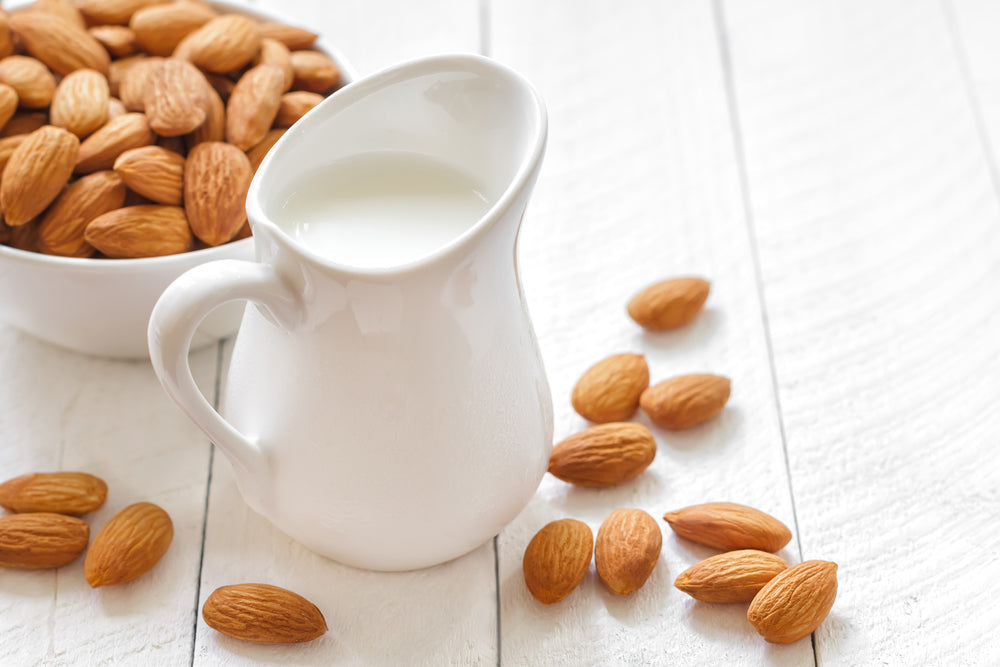 almond milk in pitcher next to almonds