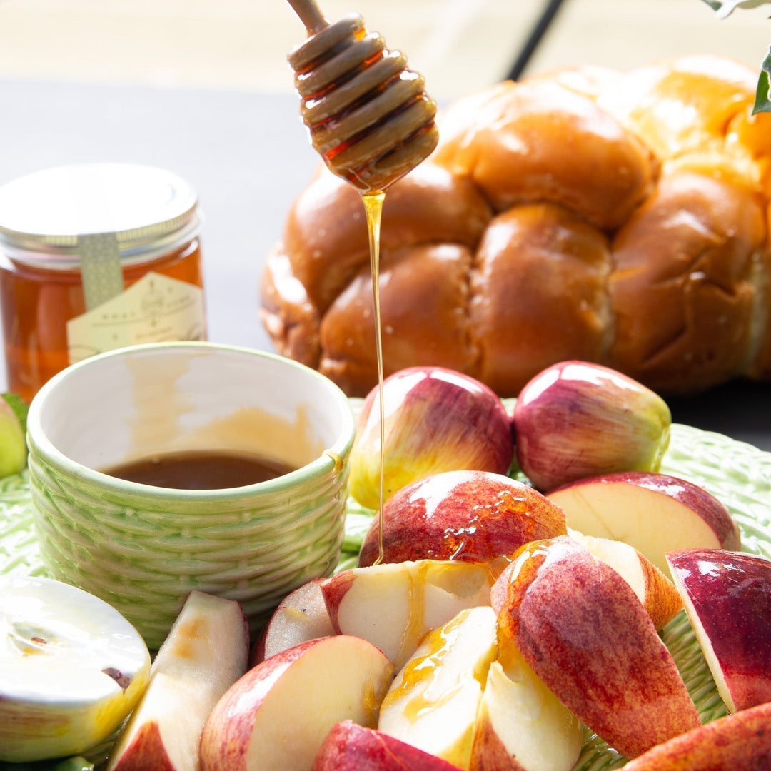 a honey dipper drizzling honey onto sliced apples