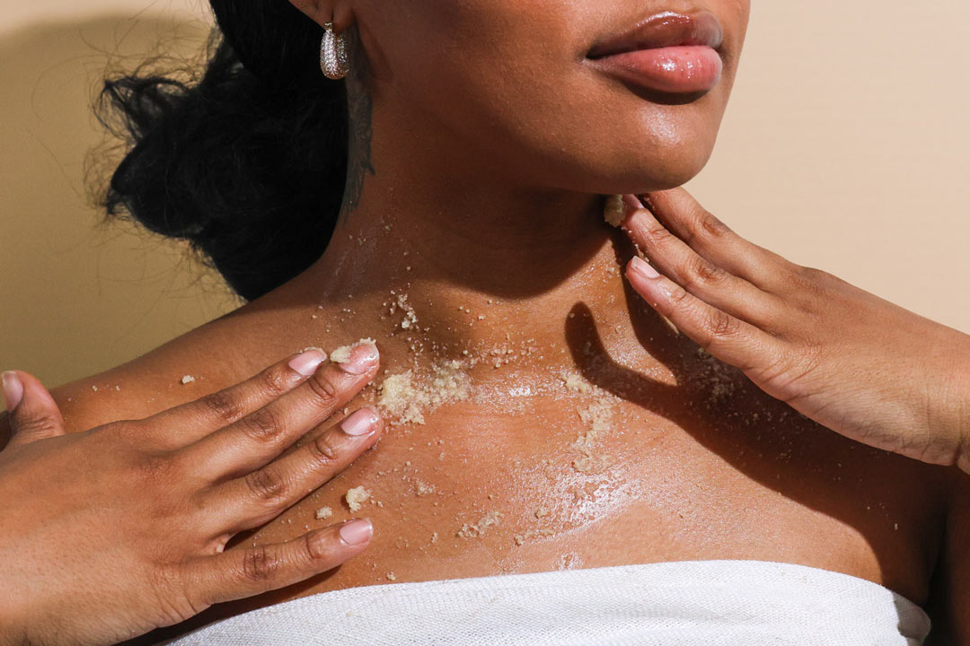 Woman applying honey body scrub on chest for gentle exfoliation and smooth skin
