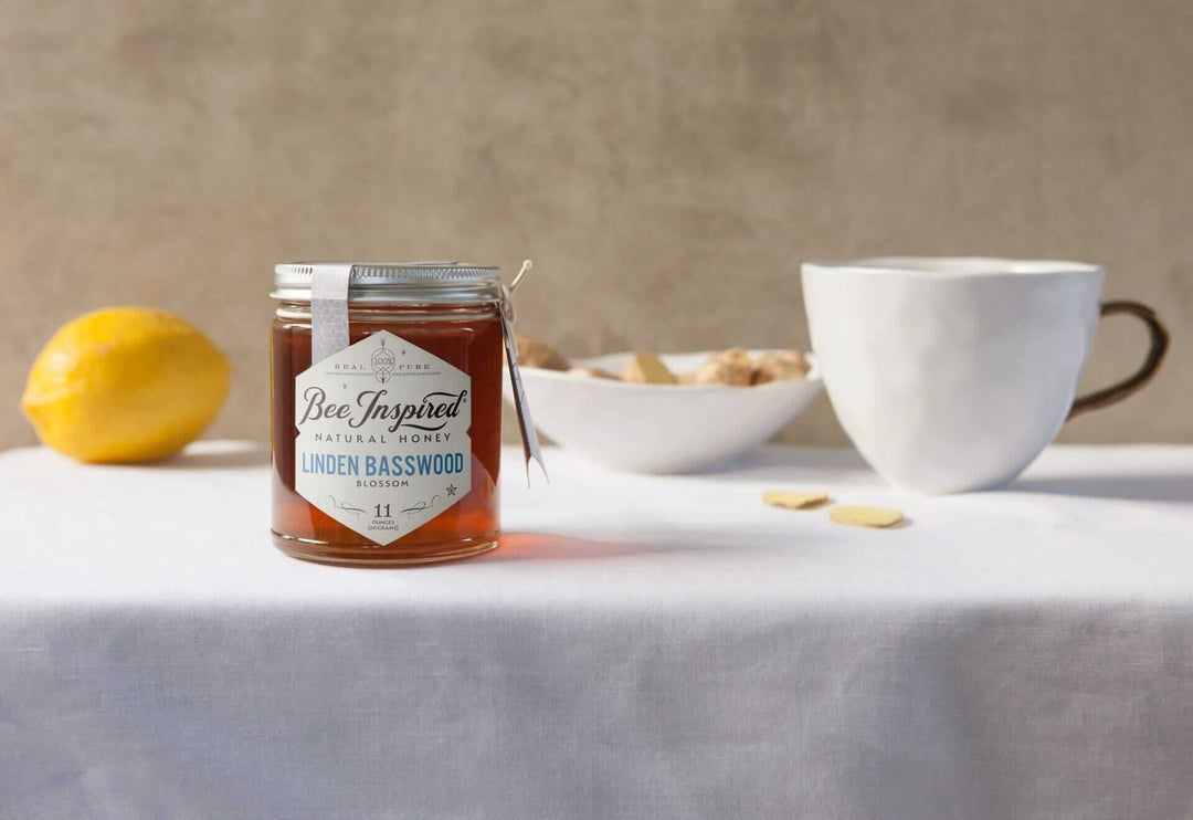 Linden Basswood raw honey jar with fresh lemon and white teacup for making ginger lemon honey tea