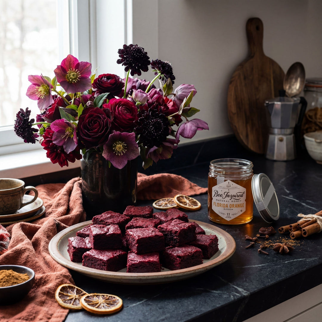 Plate of beet brownies on a kitchen counter with flowers and honey.