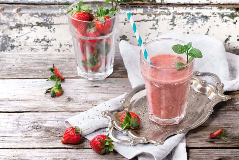 peanut butter and strawberry smoothie with fresh strawberries on a wood table