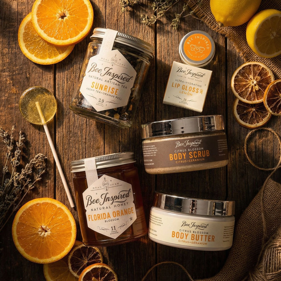 Bee-inspired Citrus Lovers Experience products including lip gloss, body scrub, and body butter on a wooden surface with oranges and lemons.