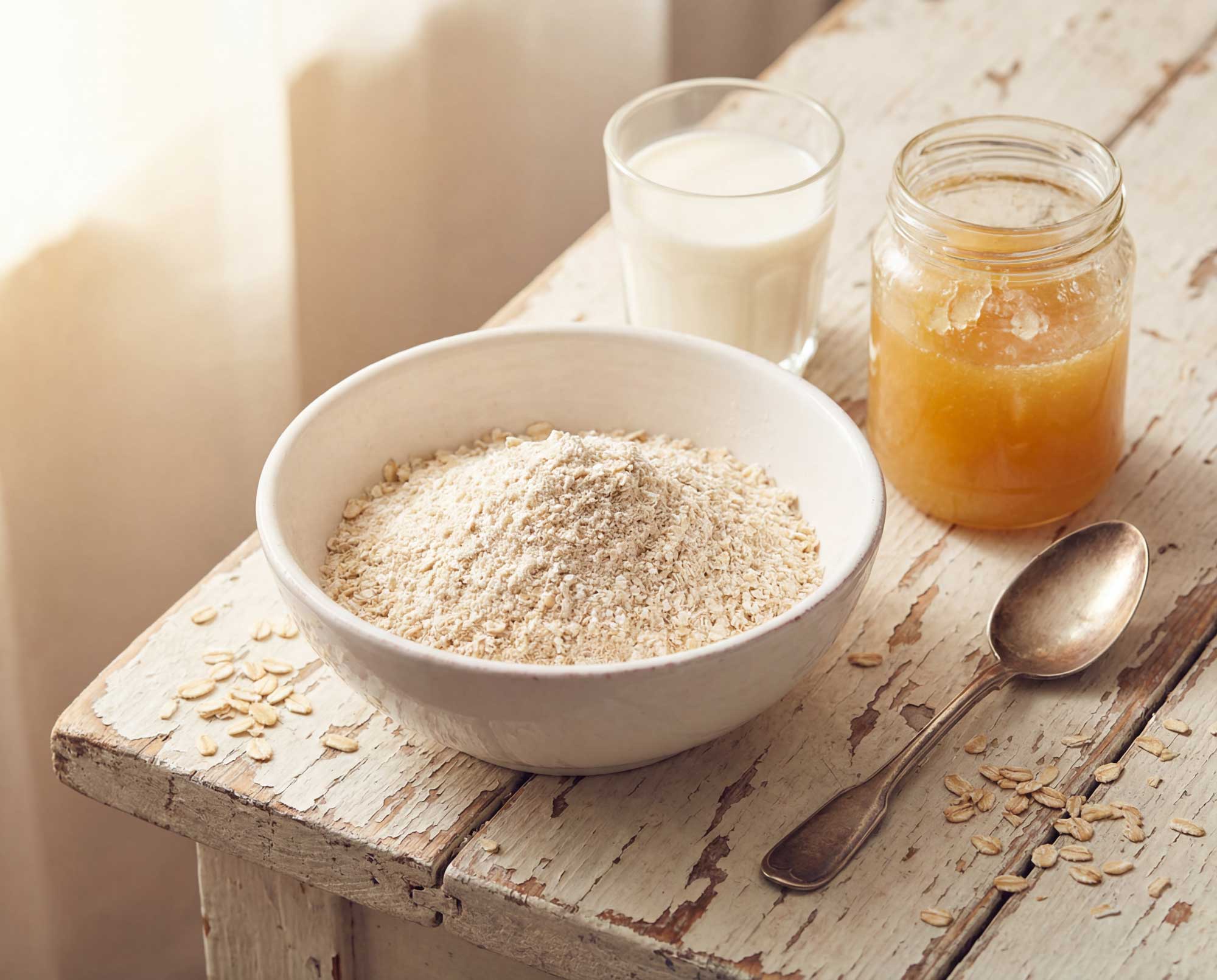 a bowl of oats, glass of milk, and jar of honey