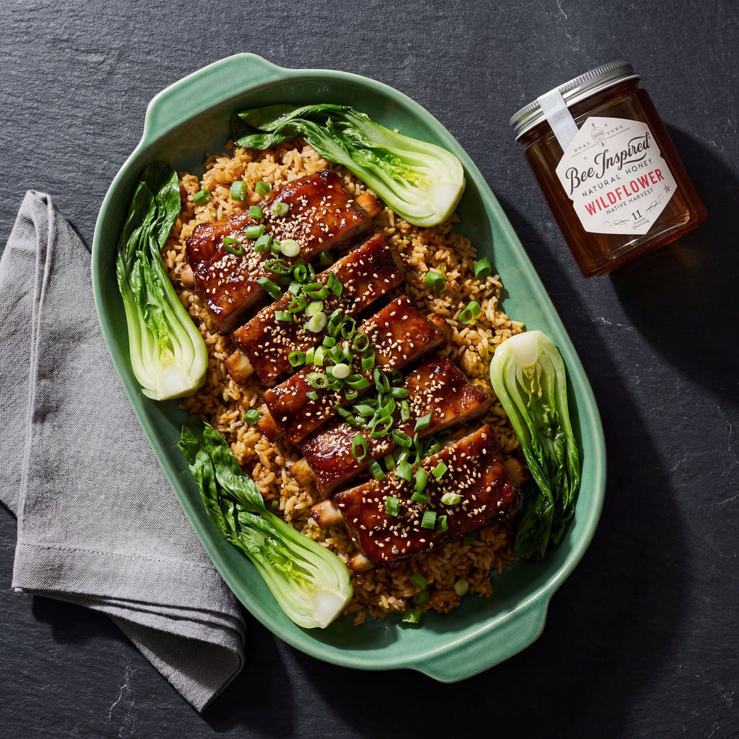 Plated dish of Korean BBQ Ribs with rice and greens, accompanied by a jar of wildflower honey on a dark surface.