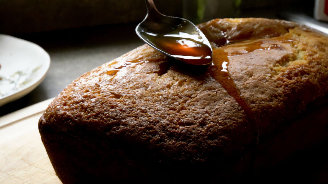 A cake loaf with a spoon drizzling honey on top.