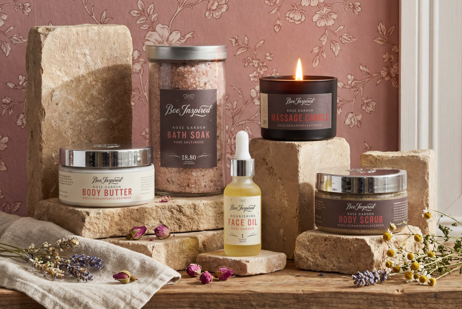 Collection of natural skincare products from the Spring Awakening collection including a candle, jars, and bottles on a wooden surface with a floral wallpaper background.