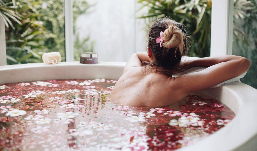 a woman bathing in a tub full of flower blossoms