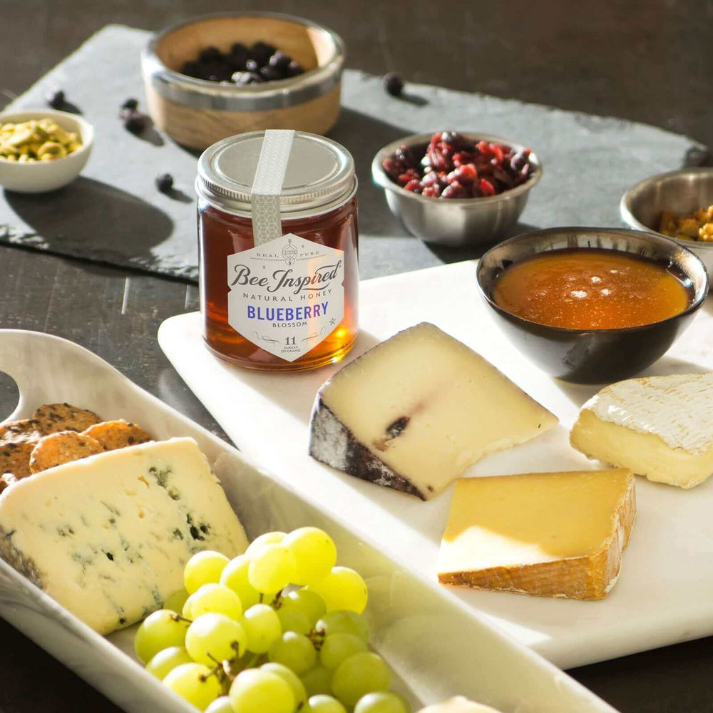 A charcuterie board with Blueberry honey, grapes, cheese, and dried fruit 