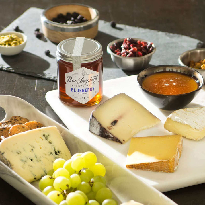 A charcuterie board with Blueberry honey, grapes, cheese, and dried fruit 