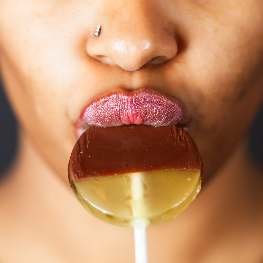 A woman eating a chocolate-dipped lollipop 