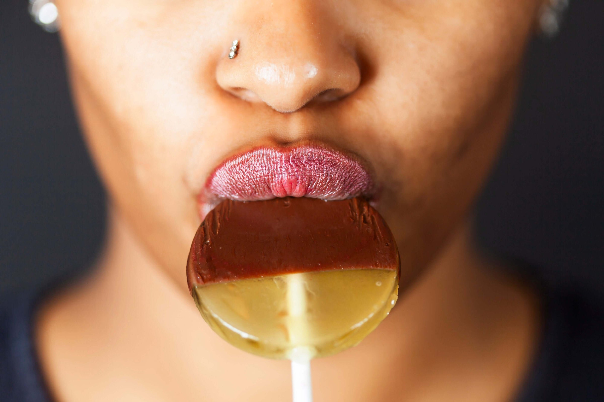 Close-up of a woman eating a chocolate-dipped honey lollipop 