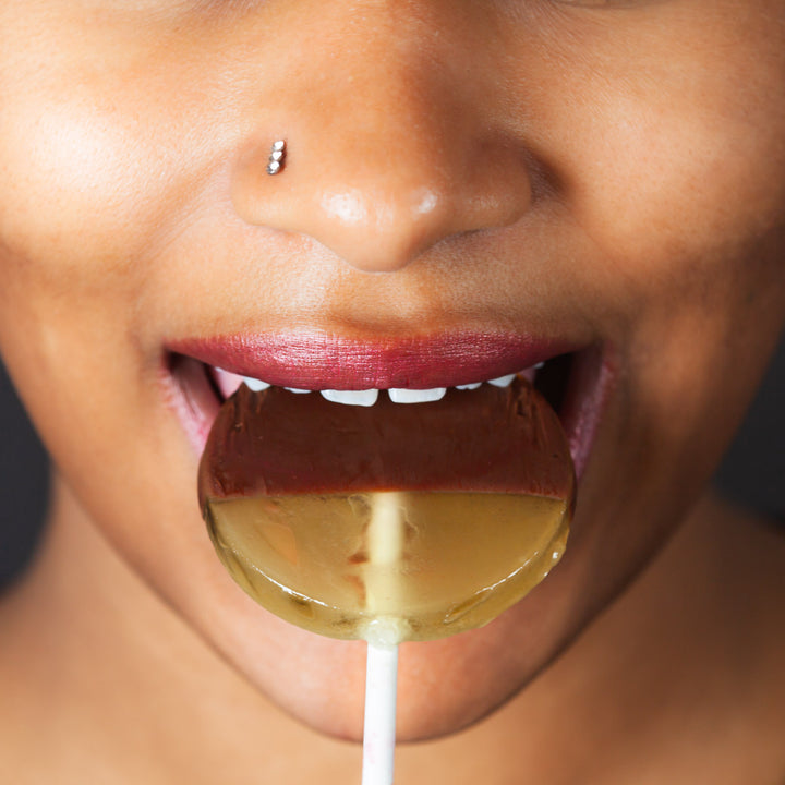 A woman eats a chocolate-dipped lollipop