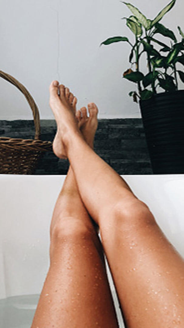 A person's feet hang out of a bathtub 