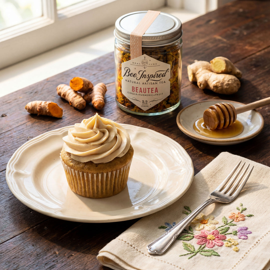 Cupcake on a plate with a jar of tea, turmeric, and honey on a wooden table.