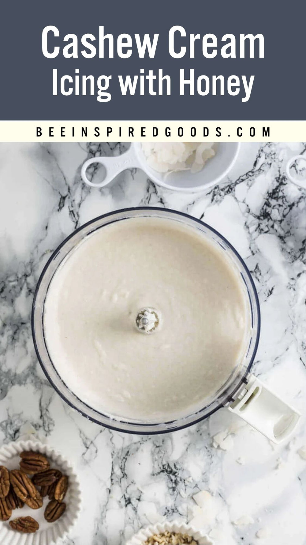 Overhead view of a creamy off-white cashew cream mixture in a blender bowl on a white marble surface, with text reading 'Cashew Cream Icing with Honey' and 'BEEINSPIREDGOODS.COM' at the top.